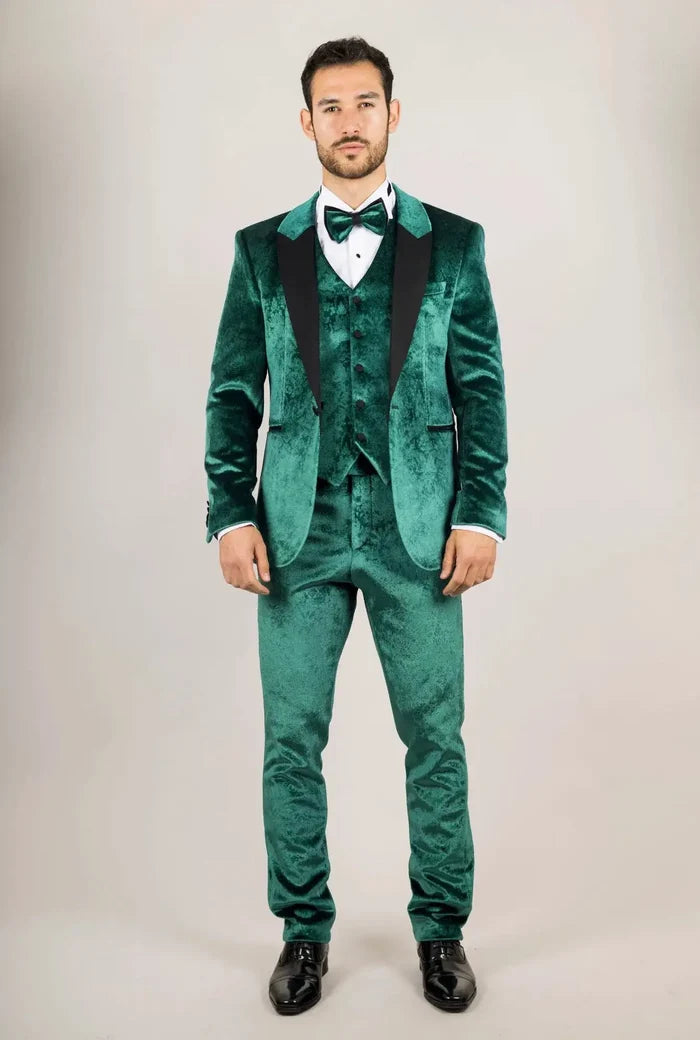 Front view of a man in a green velvet tuxedo with black lapels, matching bow tie, white shirt, and formal pose against neutral background