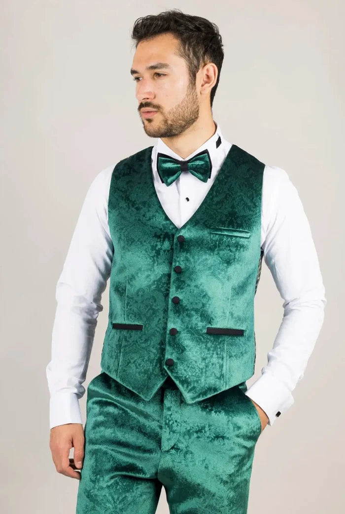 Man in a green velvet tuxedo with black lapels, matching vest, and bow tie, showing elegant formal fashion details