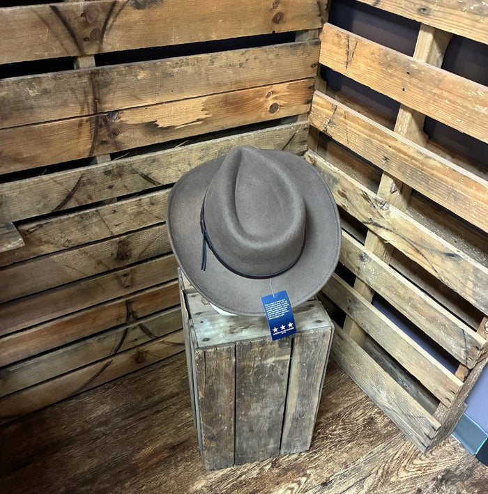 Gray fedora hat on a wooden stand with a wooden pallet background