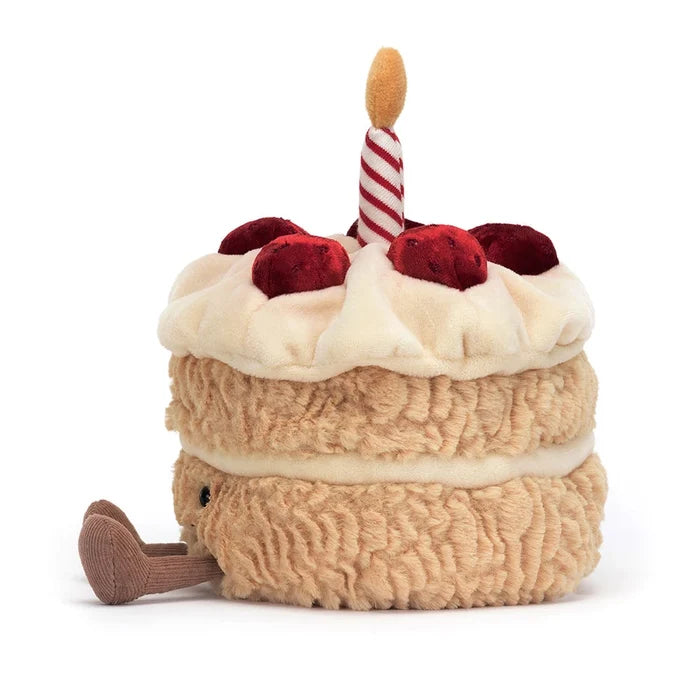 Plush toy resembling a birthday cake with berries and a candle on a white background
