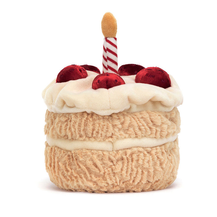 Plush toy resembling a birthday cake with candles on a white background