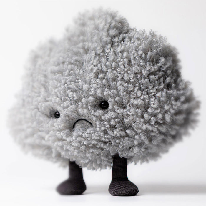 Plush toy of a grey cloud with a frowning face and black legs on a white background