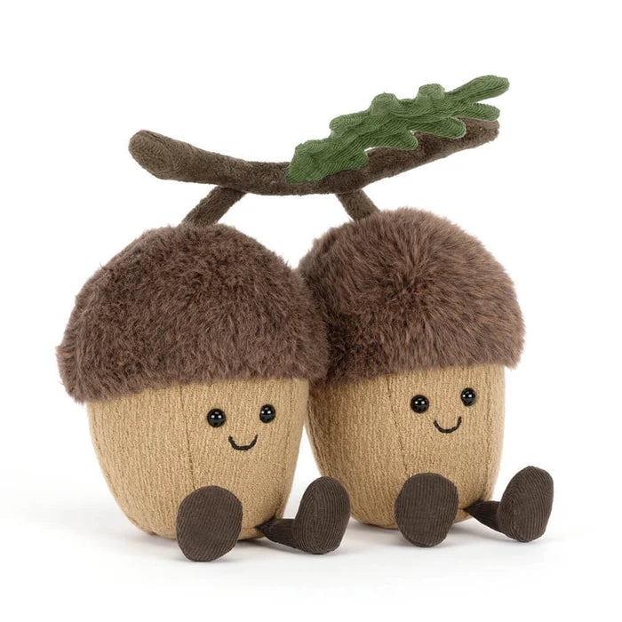 Two plush acorns with faces and a branch on a white background