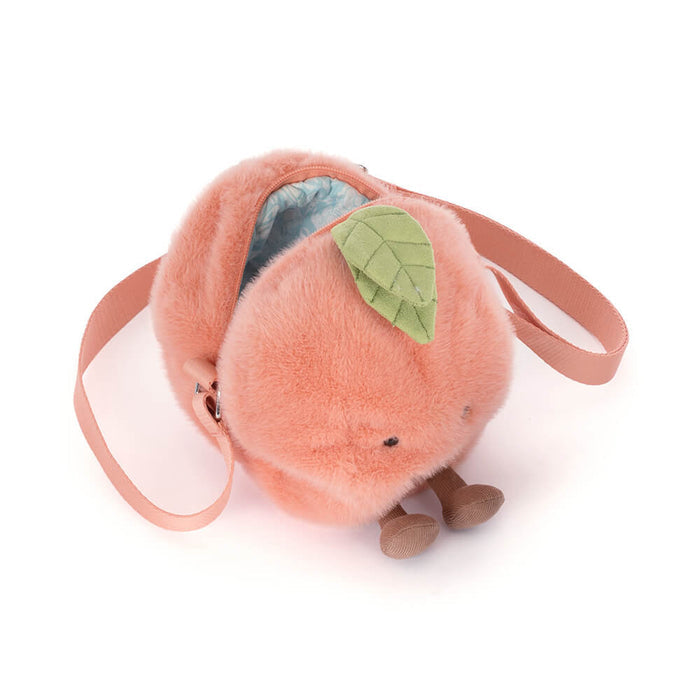 Plush peach-shaped bag with a green leaf on a white background, viewed from above showing zipper detail