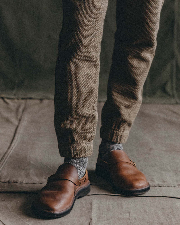 Close-up of Taylor Stitch Après Ski Pant elastic cuffs and hem in Cypress Sashiko, styled with brown leather shoes and grey socks