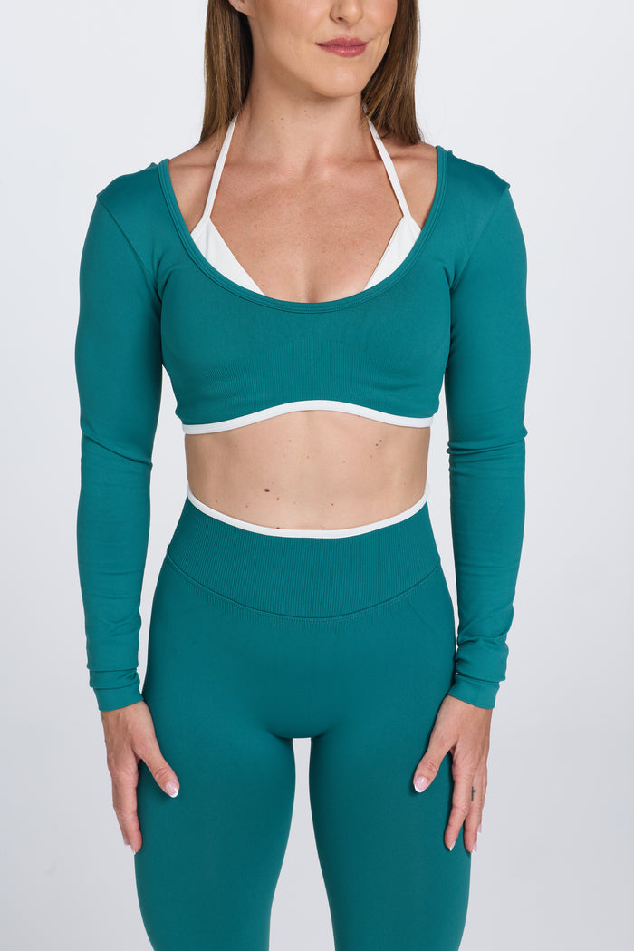 Long sleeve seamless crop top, with built in white contrasting bra, luxe white trim, and adjustable halter strap in teal colour.