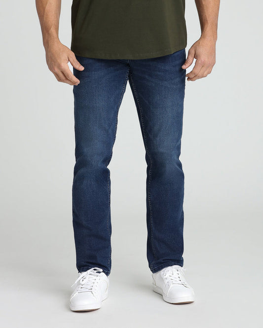 Man wearing medium blue athletic fit jeans with olive green t-shirt and white sneakers.