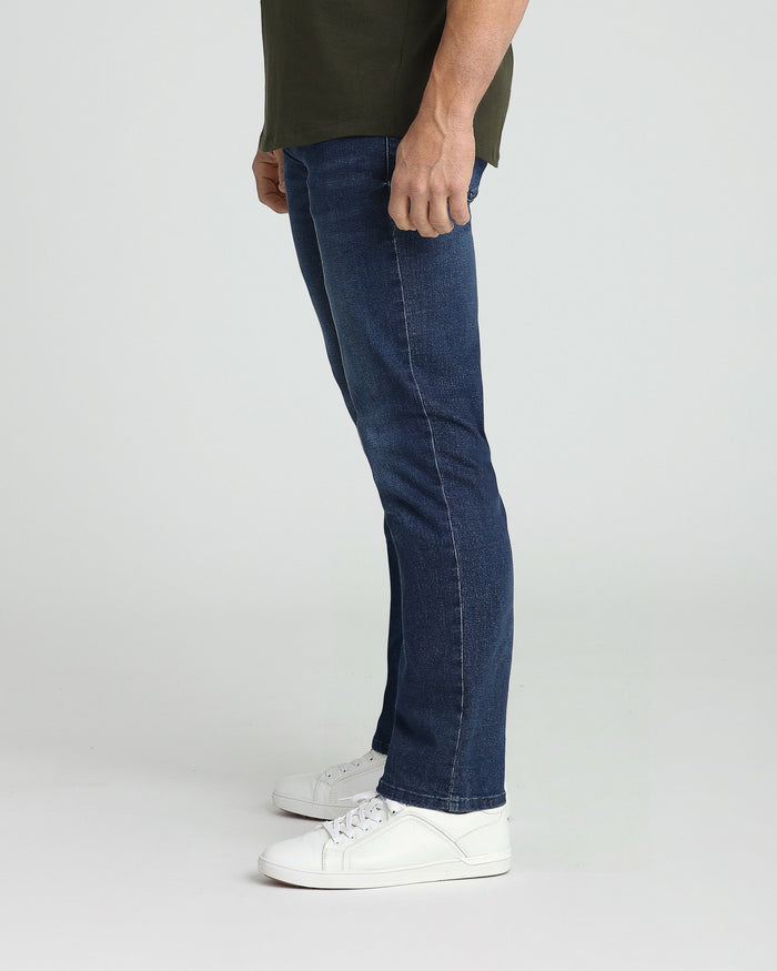 Man wearing medium blue athletic fit jeans with olive green shirt and white sneakers.