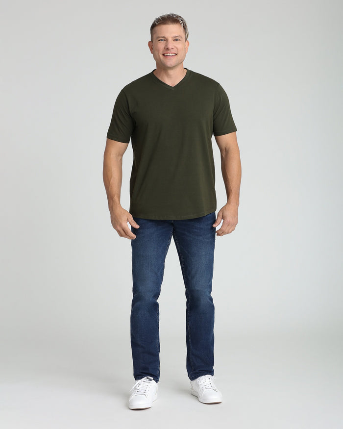 Man wearing olive green v-neck t-shirt with short sleeves and dark blue jeans.
