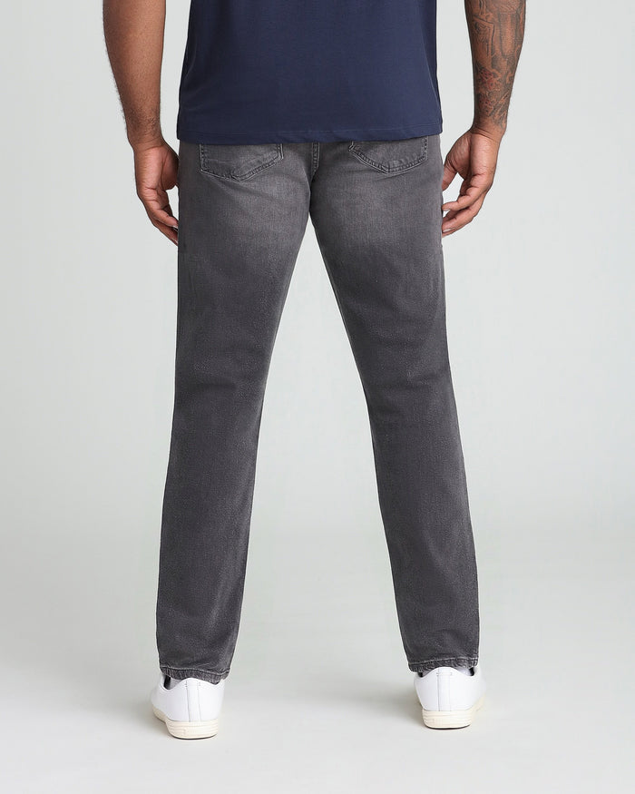 Man wearing grey athletic fit jeans with navy shirt, shown from behind.