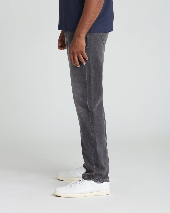 Grey athletic fit jeans on model wearing navy shirt and white sneakers.