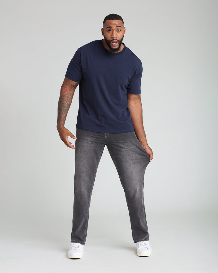Man wearing navy short-sleeve t-shirt and grey athletic fit jeans with white sneakers.