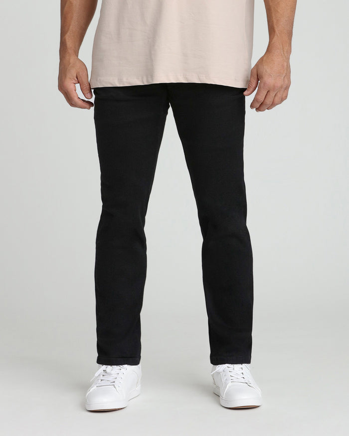 Man wearing black athletic fit jeans with cream t-shirt and white sneakers.