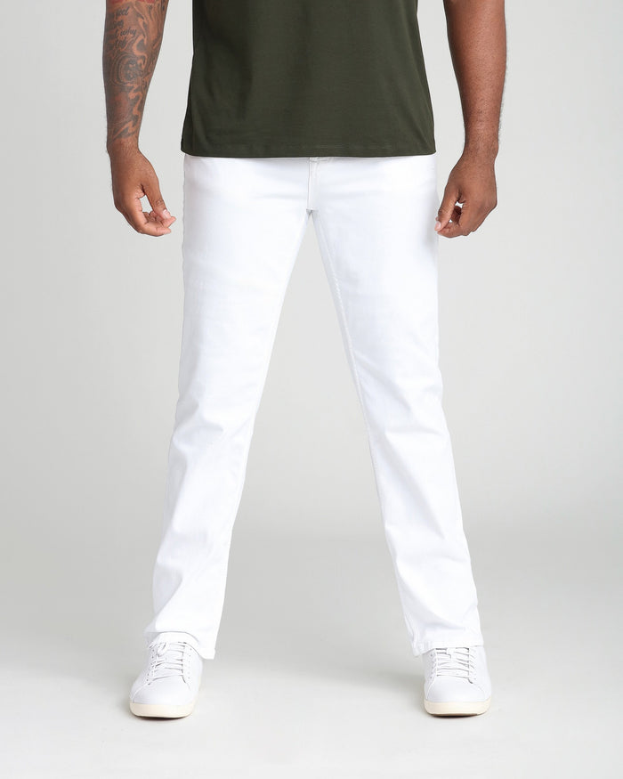 White athletic fit jeans with straight leg and white canvas sneakers.