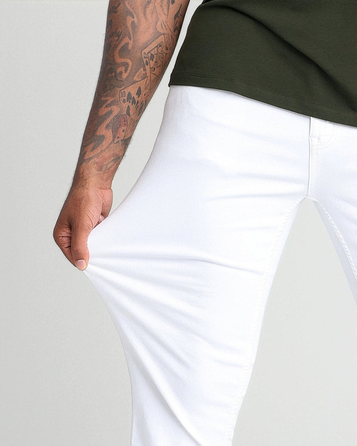 White athletic fit pants with tapered leg, shown on model wearing olive green shirt.