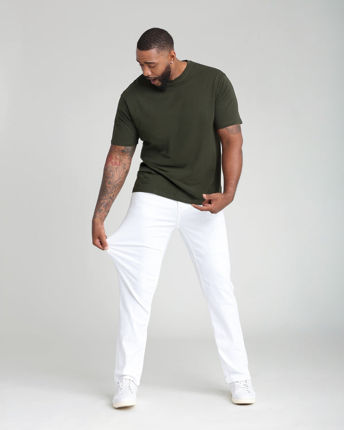Man wearing olive-green short-sleeve t-shirt with white athletic-fit pants and white sneakers.