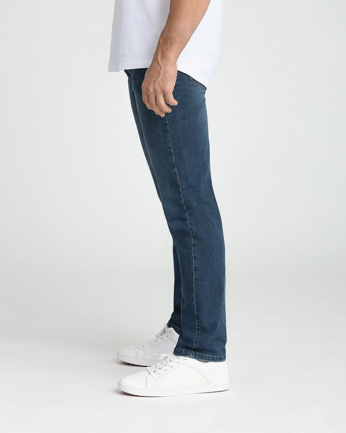 Midnight blue athletic fit jeans on model wearing white t-shirt and white sneakers.
