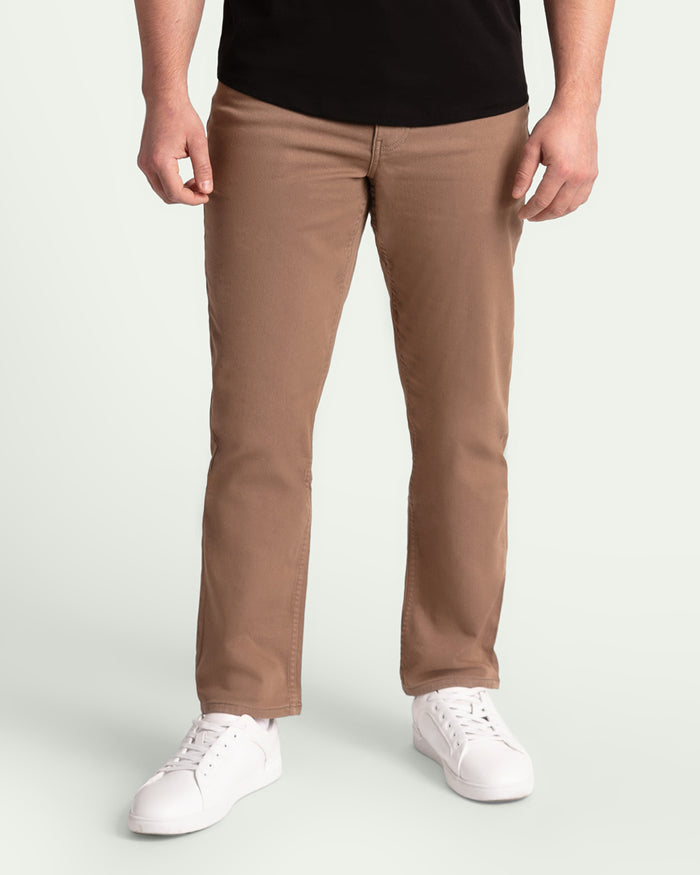 Man wearing dark khaki athletic fit pants with black shirt and white sneakers.
