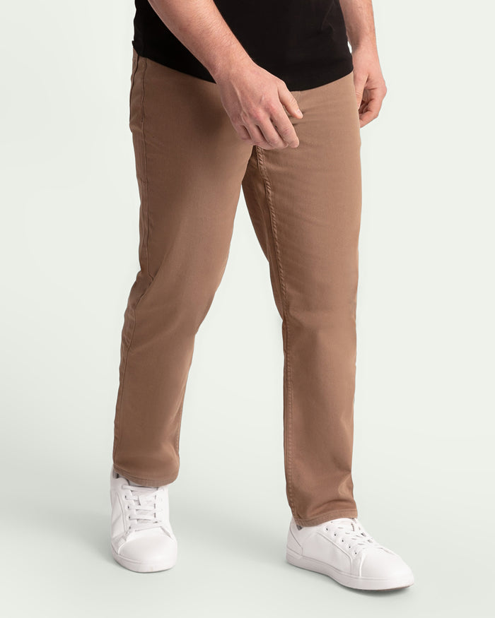 Man wearing dark khaki athletic fit pants with white sneakers and black shirt.