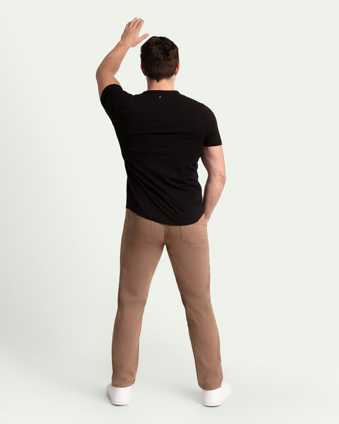 Man wearing black t-shirt and dark khaki athletic fit pants, shown from behind.