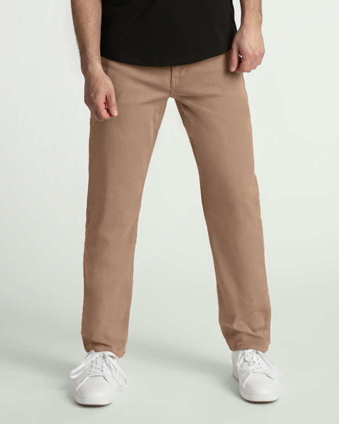 Man wearing light khaki athletic fit pants with black shirt and white sneakers.