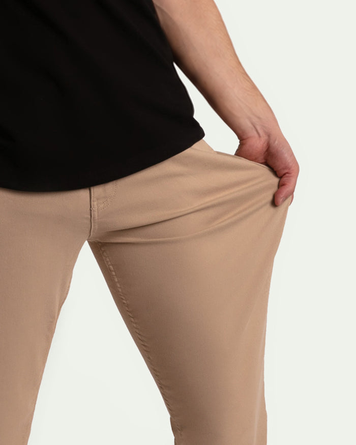 Light khaki athletic fit pants shown on model from waist down, with black shirt visible above.