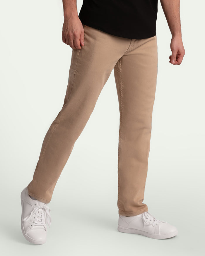 Man wearing light khaki athletic fit pants with black shirt and white sneakers.