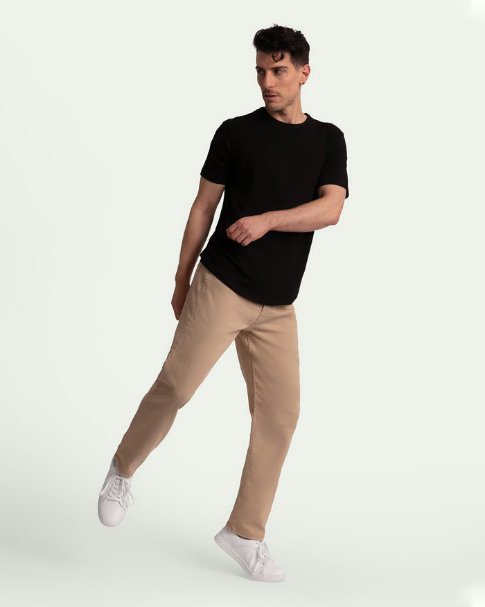 Man wearing black short-sleeve t-shirt and light khaki athletic fit pants with white sneakers.