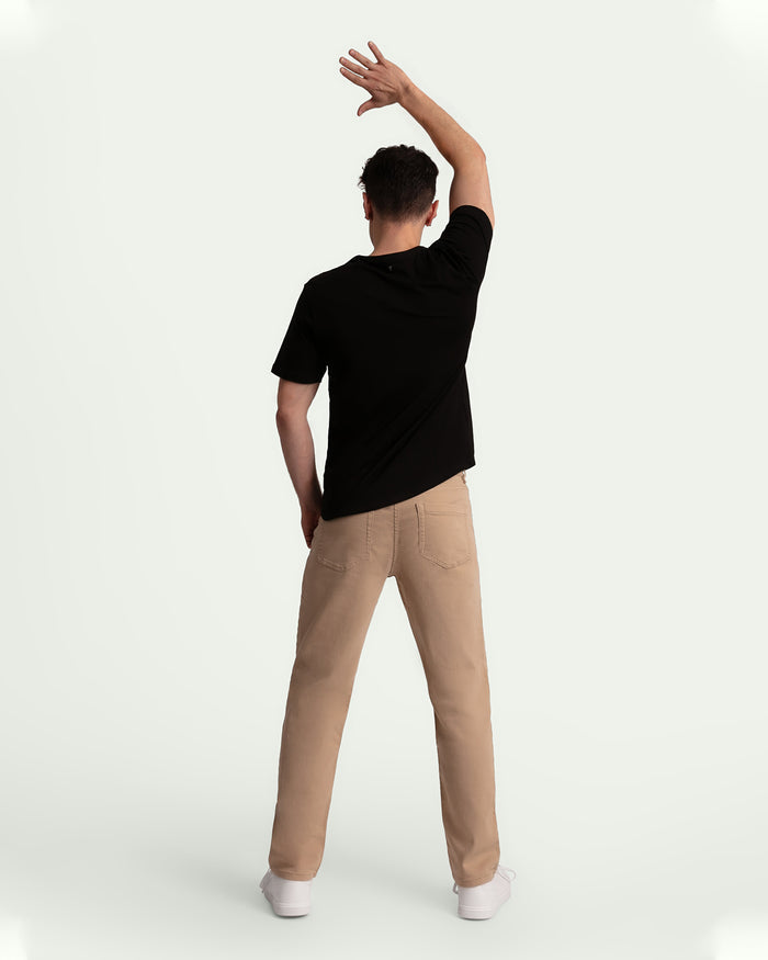 Man wearing light khaki athletic fit pants with black short-sleeve shirt, shown from behind.
