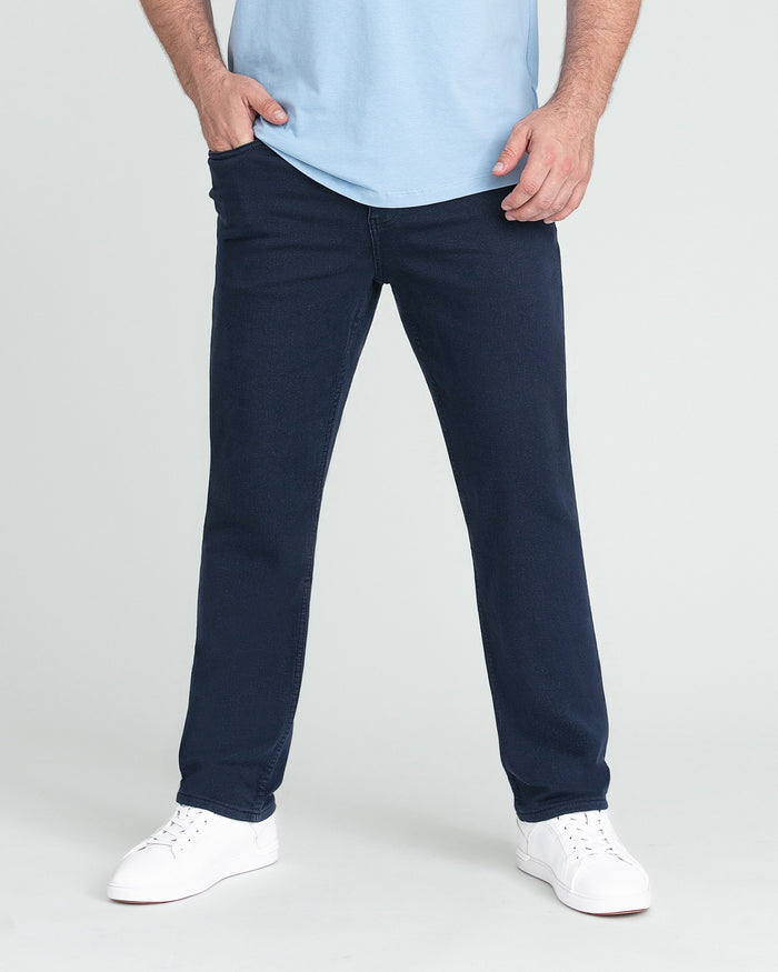 Man wearing light blue t-shirt and navy athletic fit jeans with white sneakers.