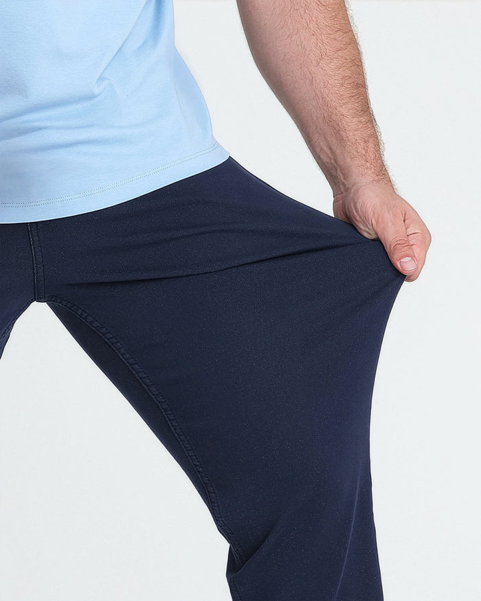 Man wearing light blue tank top and navy athletic fit pants with visible seam stitching.