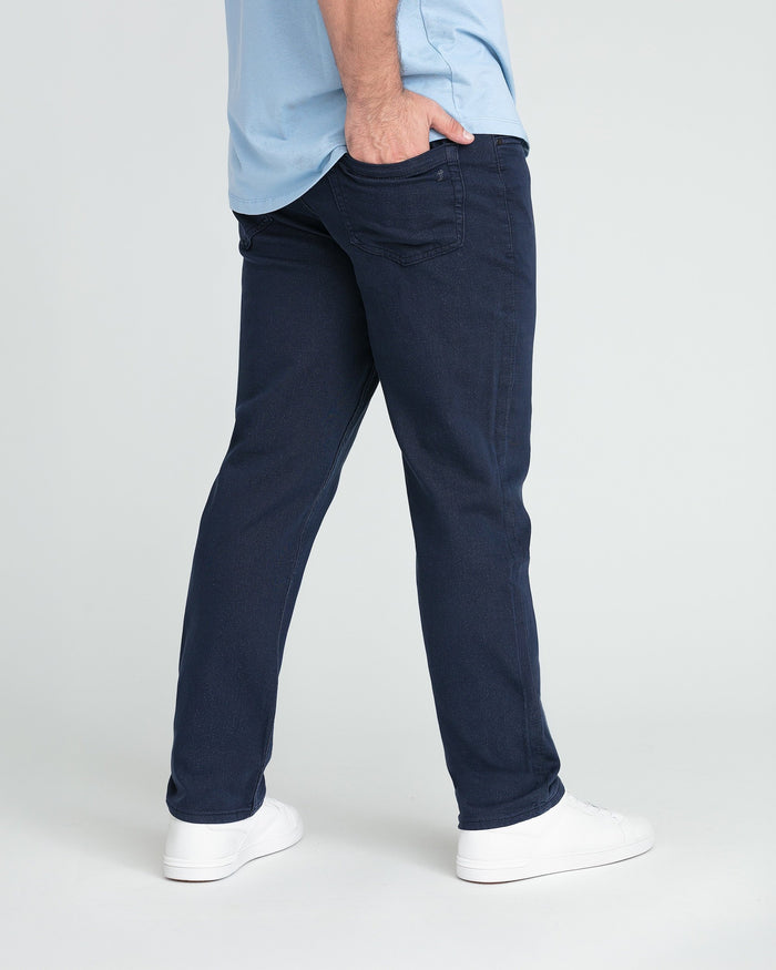 Man wearing navy athletic fit jeans with light blue shirt and white sneakers.