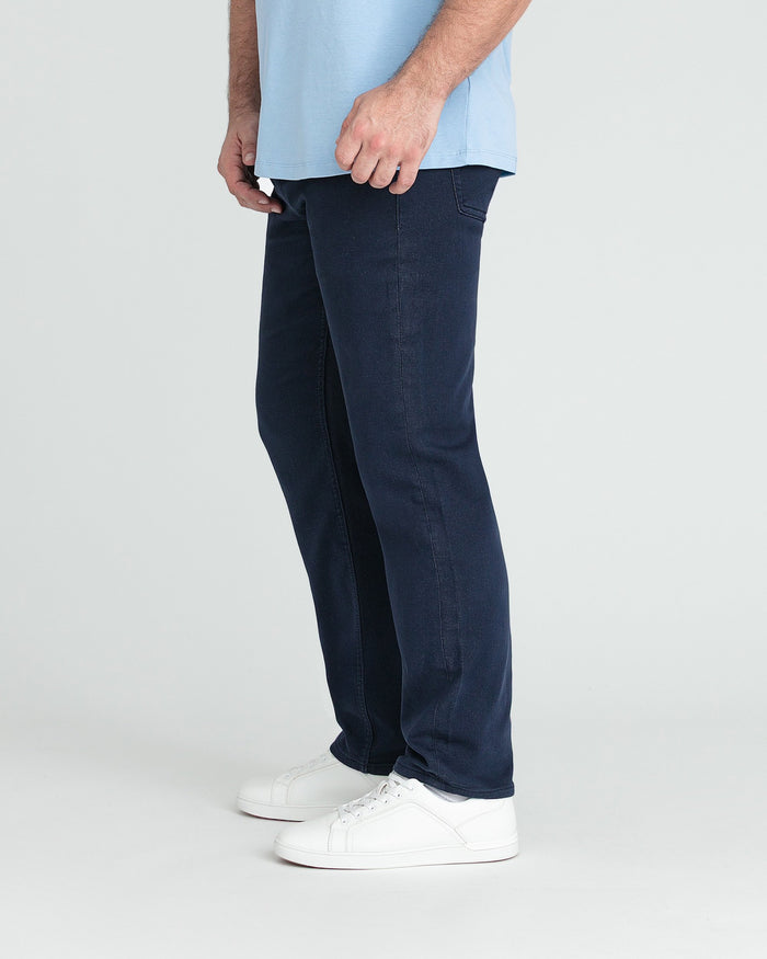 Man wearing light blue shirt and dark navy athletic fit jeans with white sneakers.