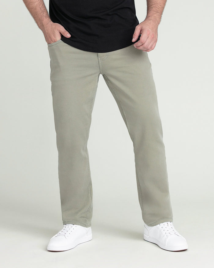 Man wearing light green athletic fit pants with black t-shirt and white sneakers.