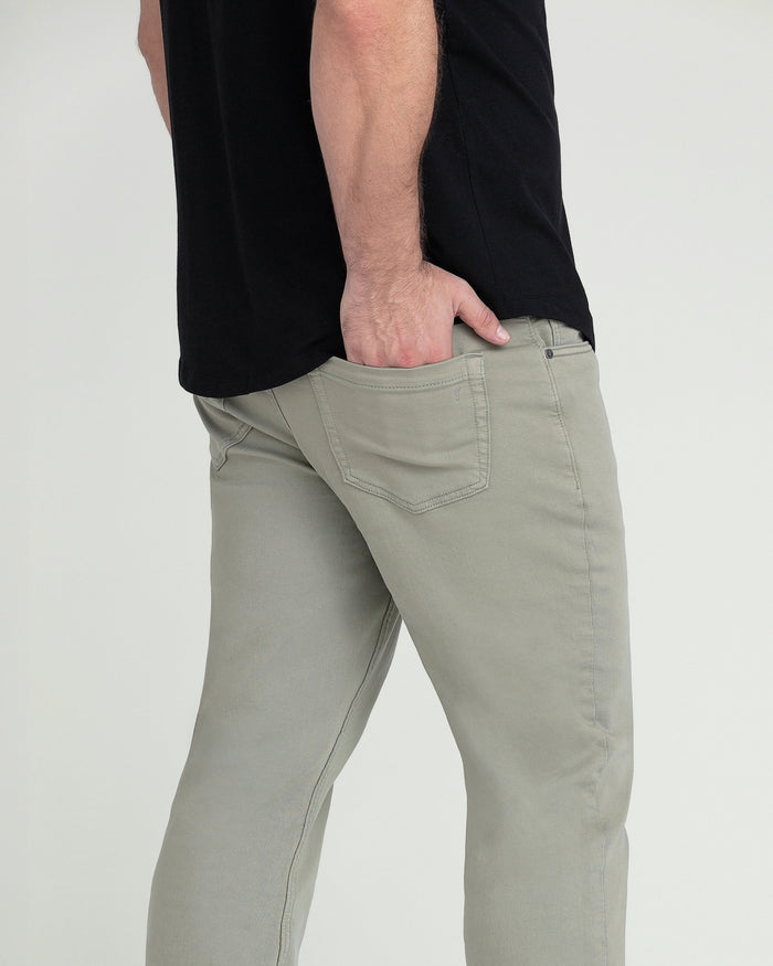 Light green athletic fit pants with five-pocket styling worn with a black shirt.