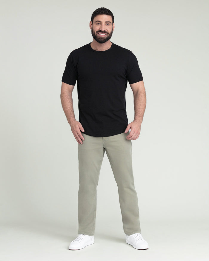 Man wearing black short-sleeve t-shirt and light sage green athletic fit pants with white sneakers.