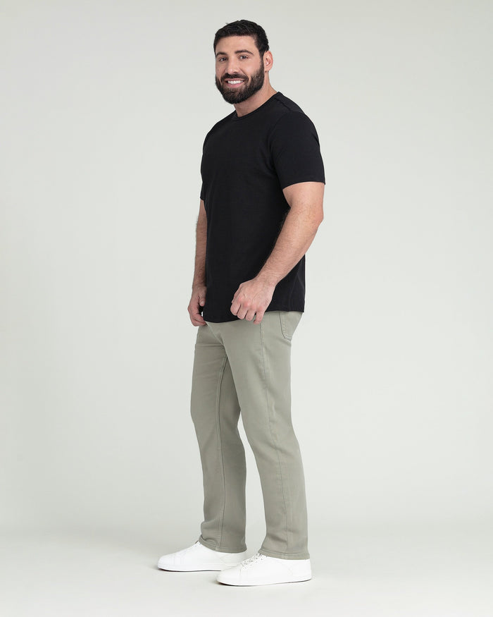Man wearing black short-sleeve t-shirt and light sage green athletic fit pants with white sneakers.