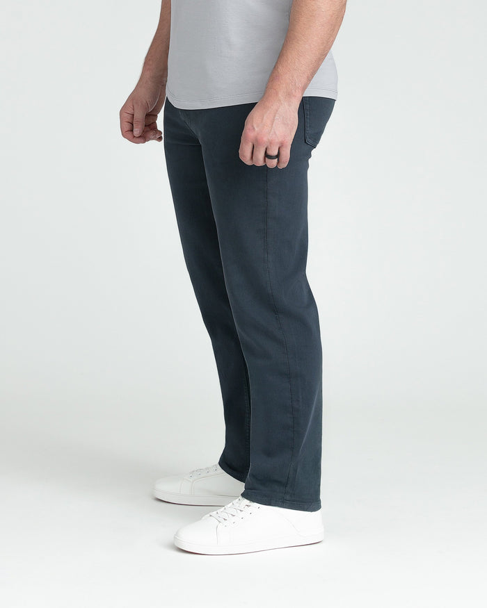 Man wearing slate-colored athletic fit pants with light gray t-shirt and white sneakers.