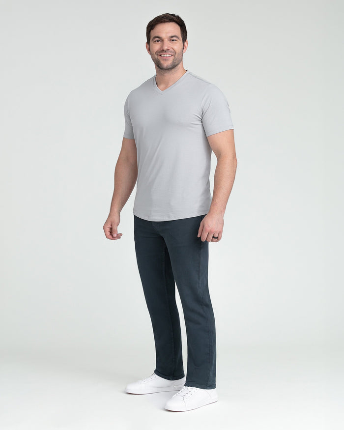 Man wearing slate gray v-neck t-shirt and dark blue athletic fit pants with white sneakers.