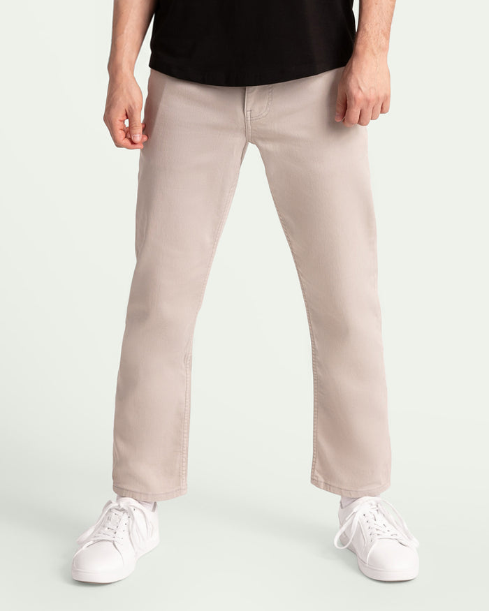 Man wearing light grey athletic fit chinos with black shirt and white sneakers.