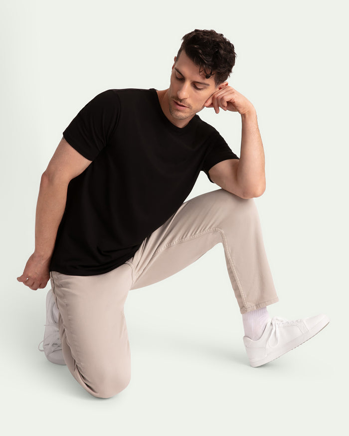 Man wearing black short-sleeve t-shirt and light grey athletic fit pants with white sneakers.
