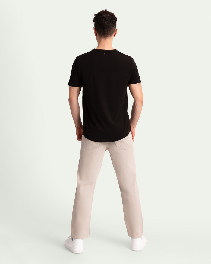 Man wearing black short-sleeve t-shirt and light grey athletic fit pants, shown from back view.