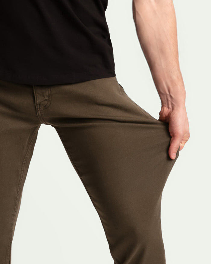 Olive tapered pants on man wearing black shirt, shown from waist down on neutral background.