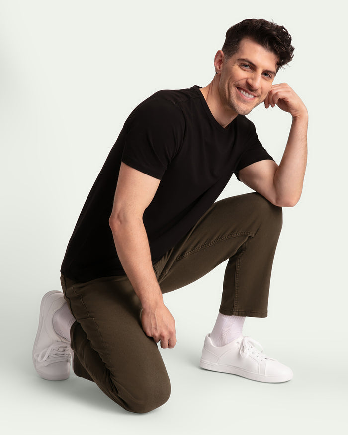 Man wearing black v-neck t-shirt and olive athletic fit pants with white sneakers.