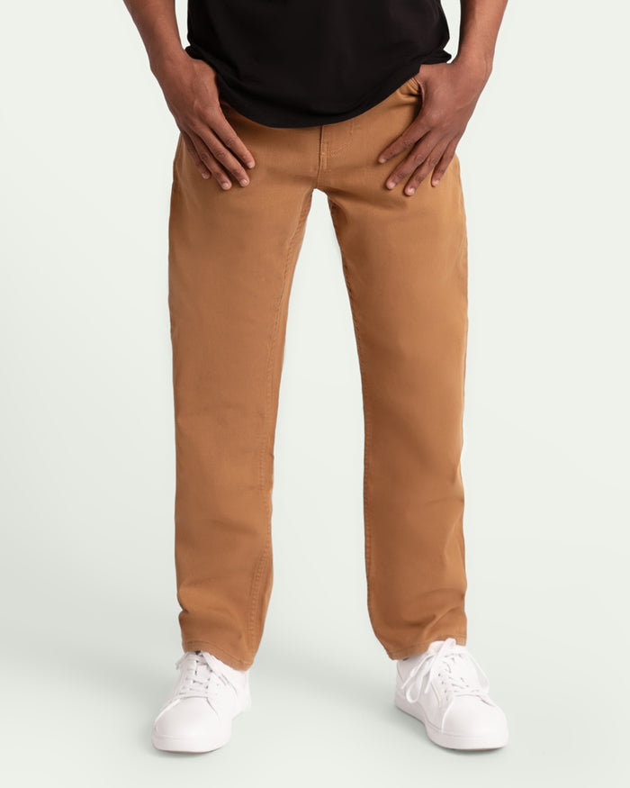 Man wearing brown athletic fit pants with black shirt and white sneakers.