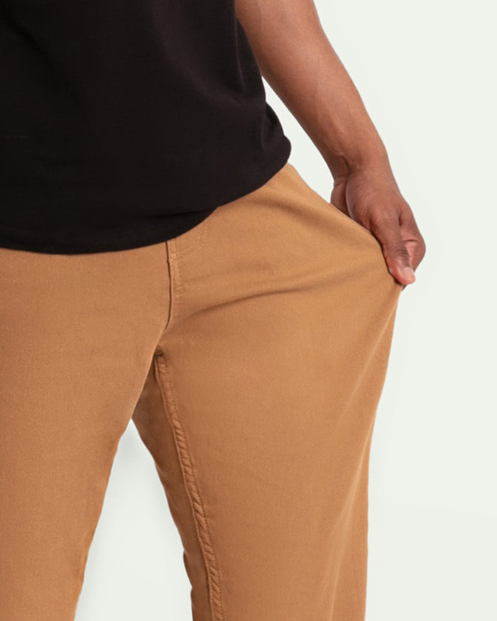 Brown athletic fit chinos with visible seam detail on person wearing black shirt.