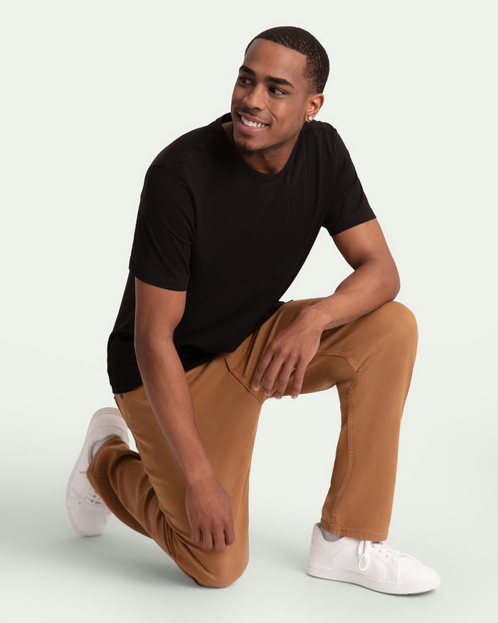 Man wearing black t-shirt and brown athletic fit pants with white sneakers.