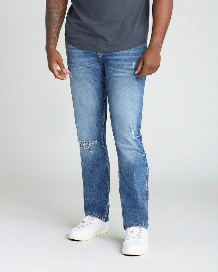 Man wearing medium blue ripped jeans with athletic fit and dark navy t-shirt.