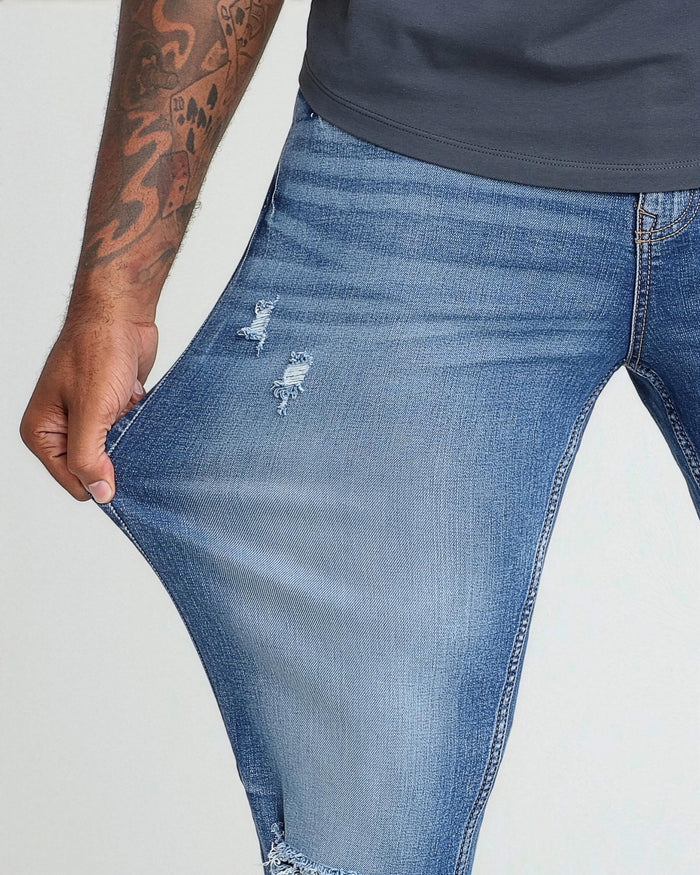 Medium blue ripped jeans with athletic fit, shown on model wearing dark gray shirt.
