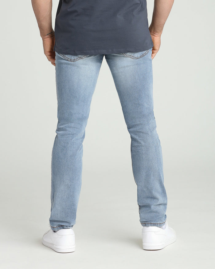 Man wearing light blue ripped jeans with athletic fit and dark gray t-shirt, back view.